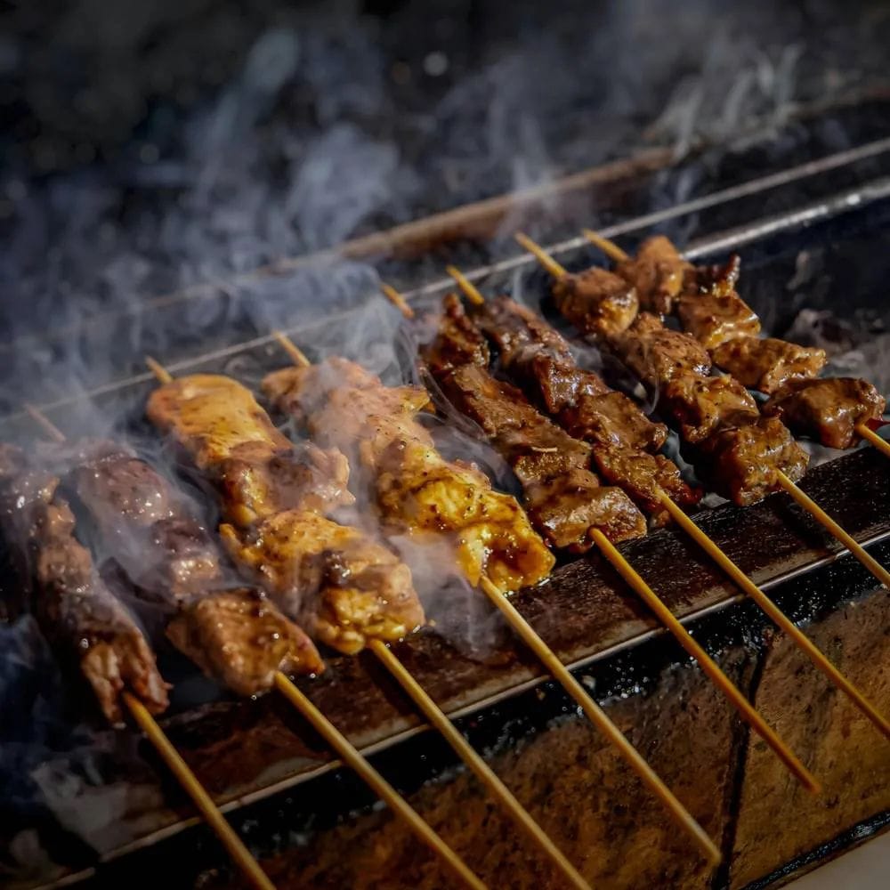 Espetinhos de frango em espetos de bambu na churrasqueira
