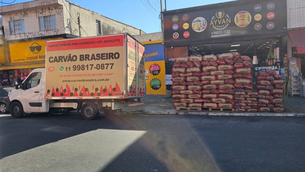 Caminhão e pilha de Carvão Braseiro em frente a comércio